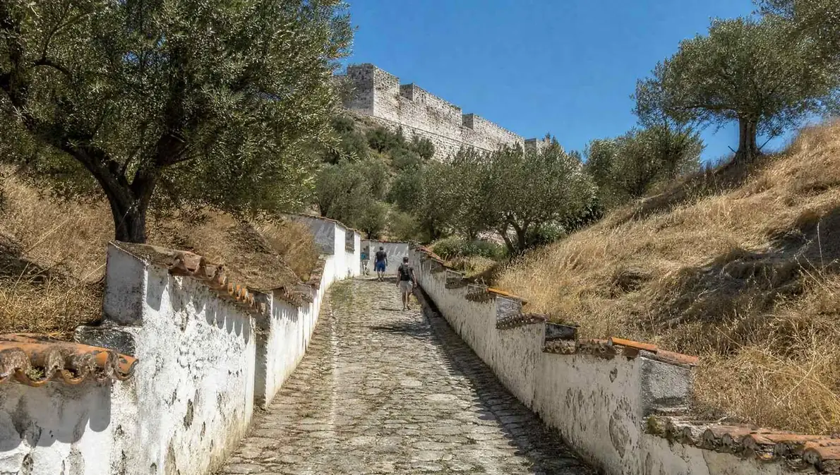 A cobbled lane climbing between whitewashed walls towards a hilltop