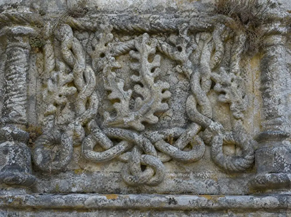 Weathered carved limestone rope mouldings and knotted cable on a wall