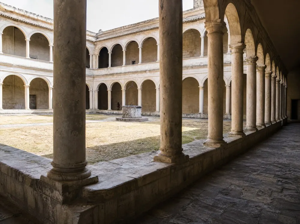 A two-storey Renaissance cloister arcade around a sunlit courtyard