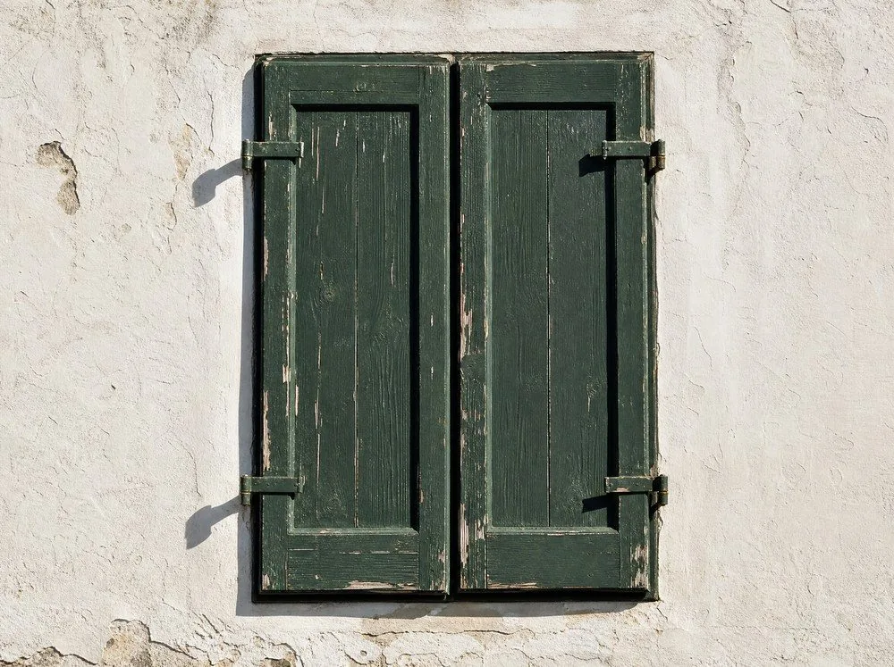 Weathered shutters on a whitewashed wall
